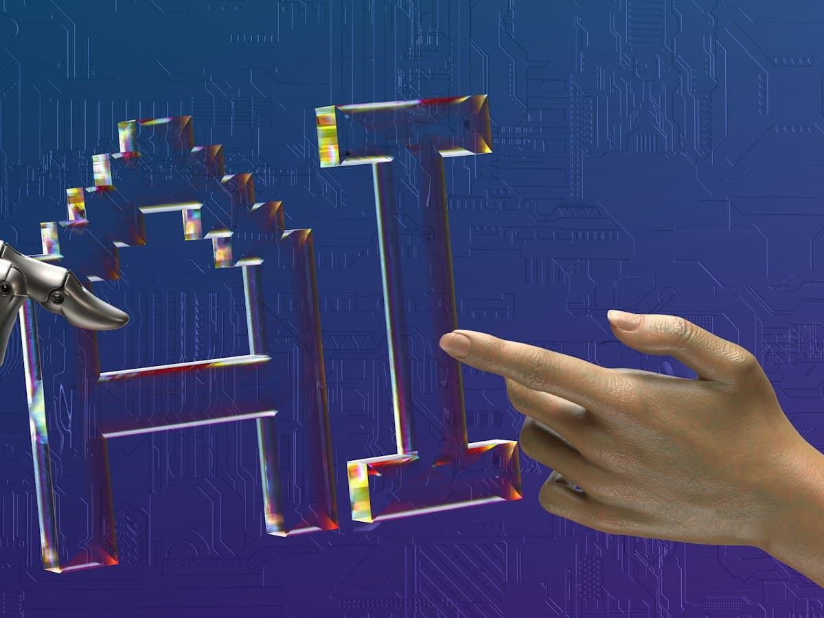 A human hand and a robot hand reaching toward the letters AI